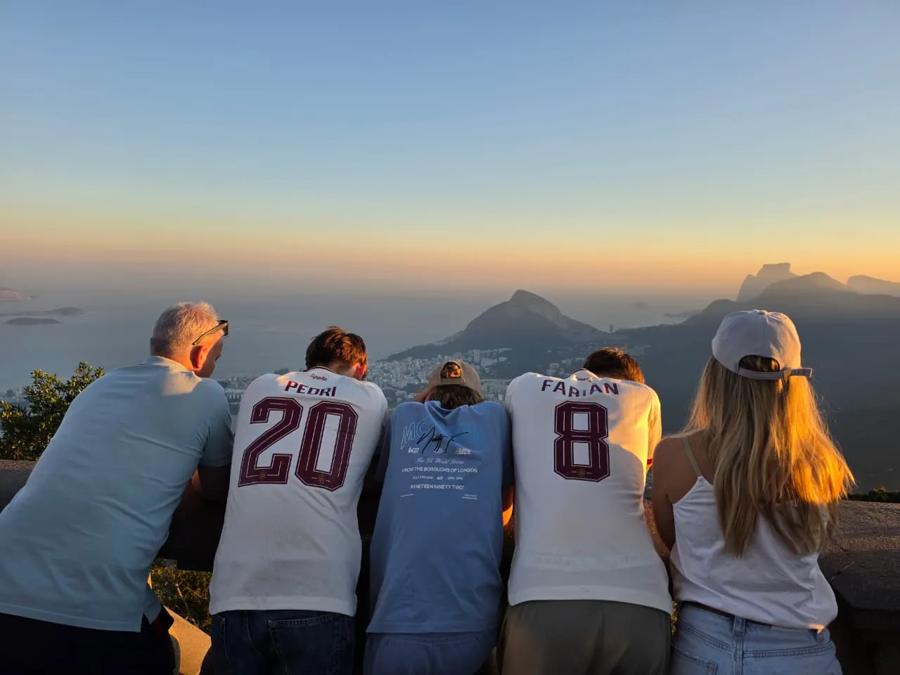 A group leaning on a viewpoint wall above Rio in golden evening light