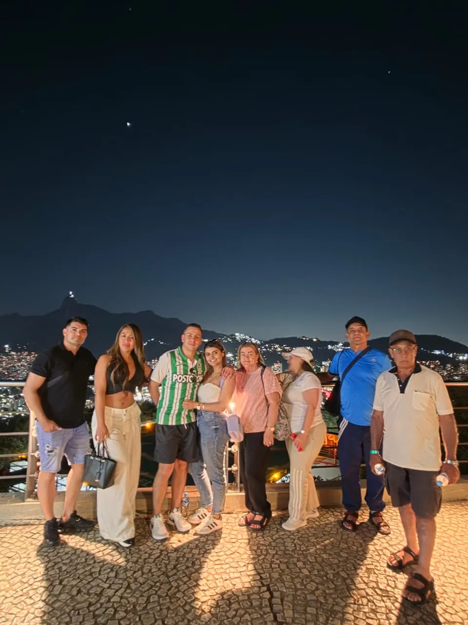 A group at a viewpoint at night with the illuminated Christ the Redeemer in the distance