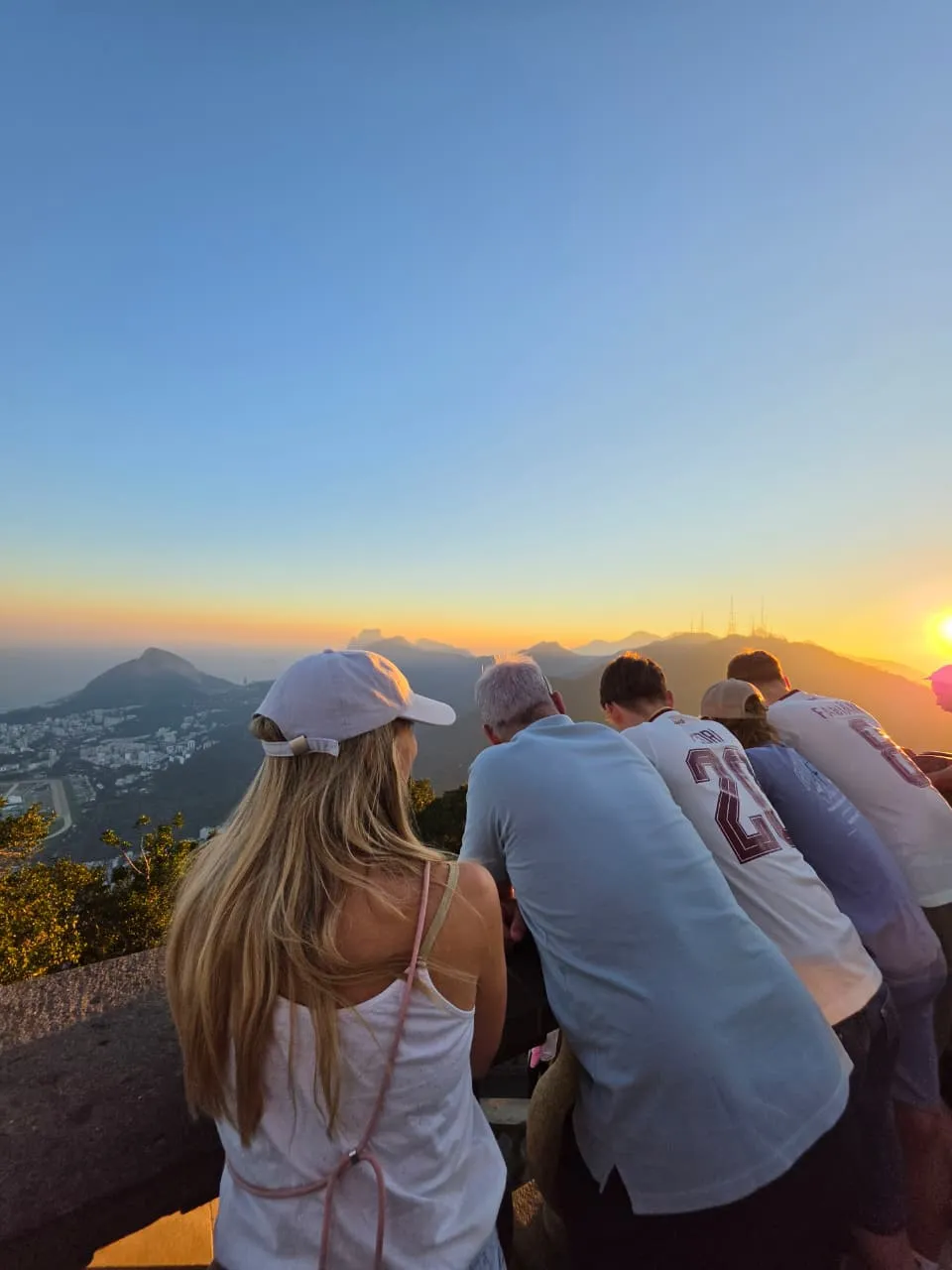 People seen from behind watching the sunset over Rio from a viewpoint